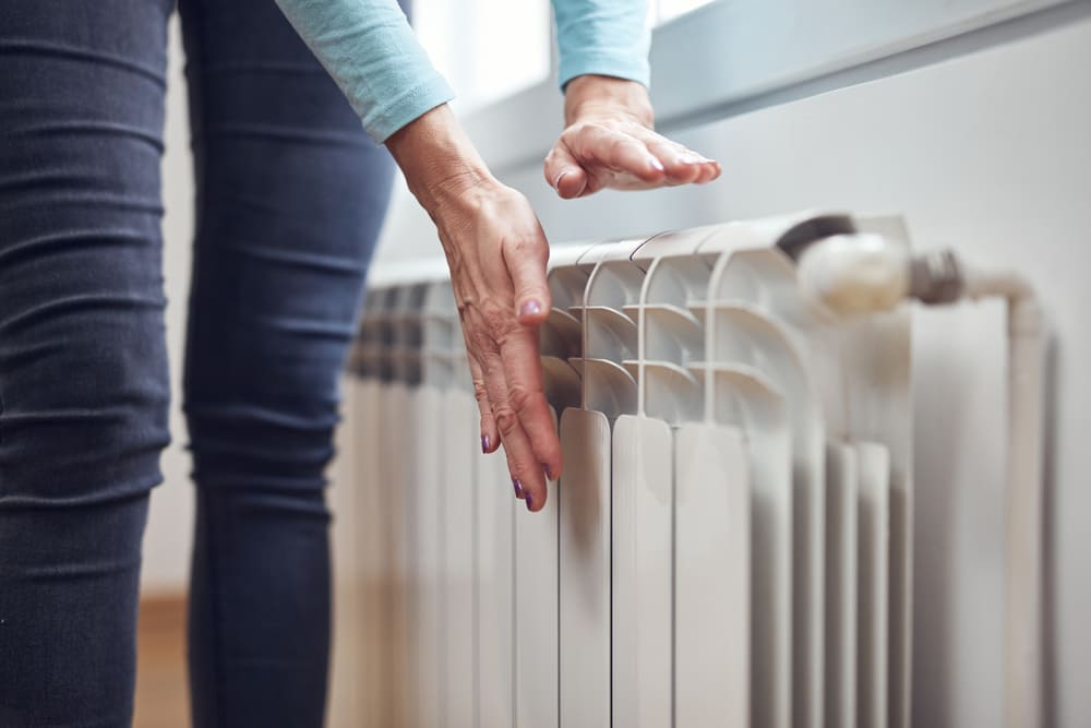 personne posant ses mains sur un radiateur